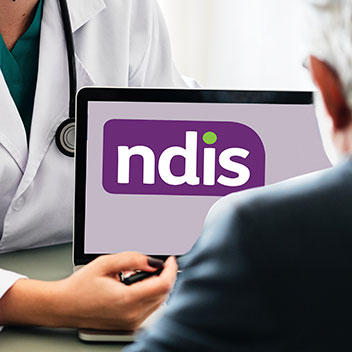 A doctor points to a computer screen with the NDIS logo.