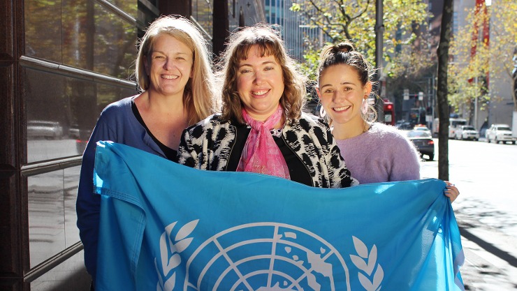 Kylee, Alanna and Courtney holding a united nations flag