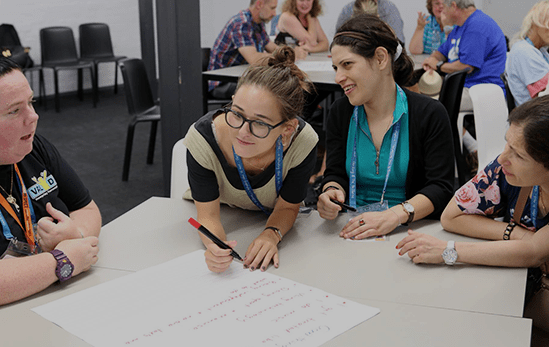A group of people writing on a piece of paper at a workshop.