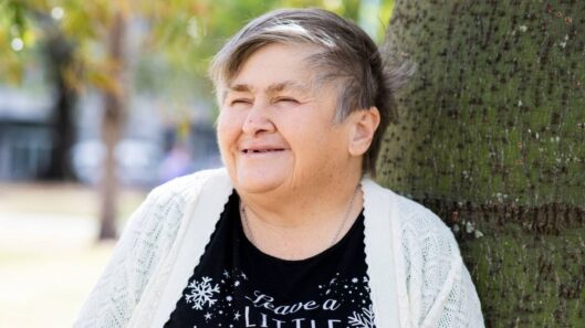 A person standing in front of a tree and smiling.