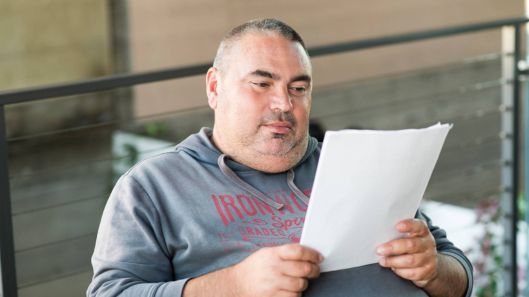 A man with intellectual disability reads a document.