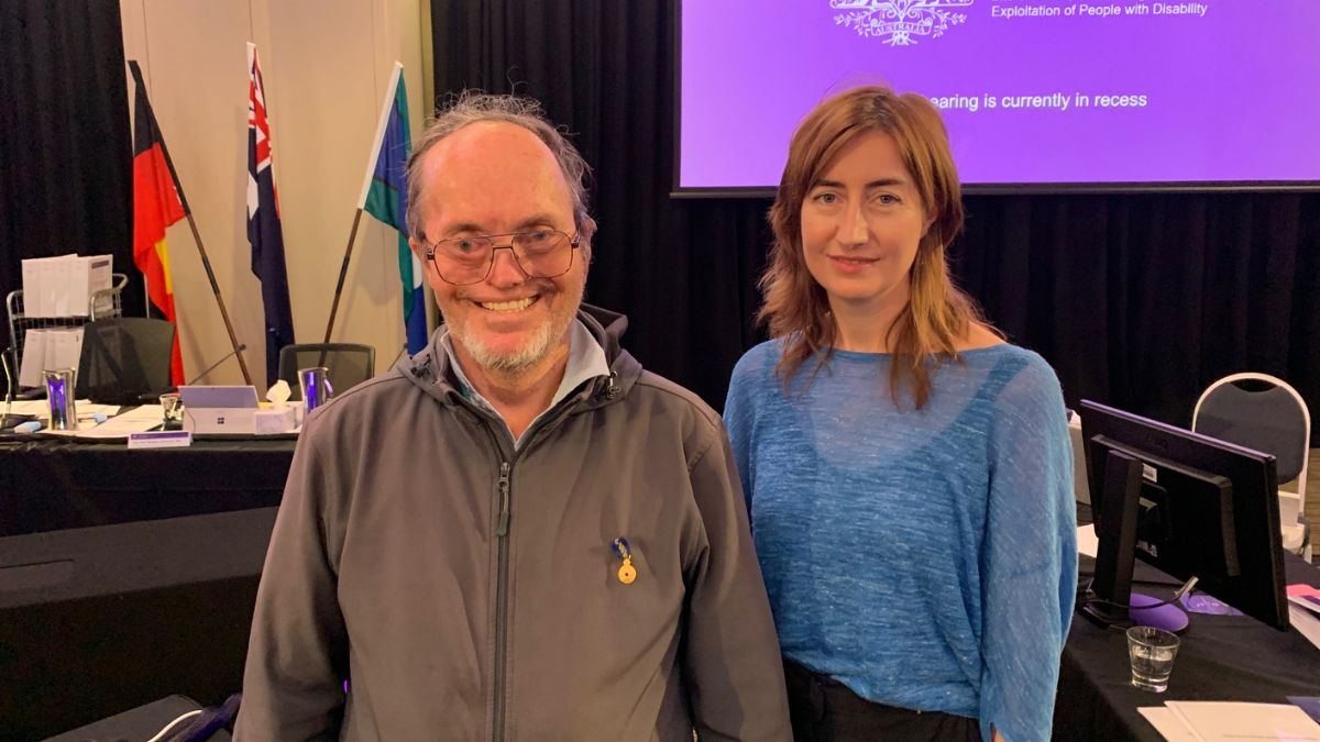 Two people stand in the Disability Royal Commission meeting room to give evidence.