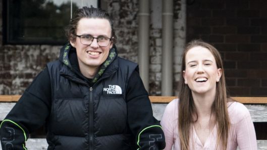 Two young people with intellectual disability smiling together.