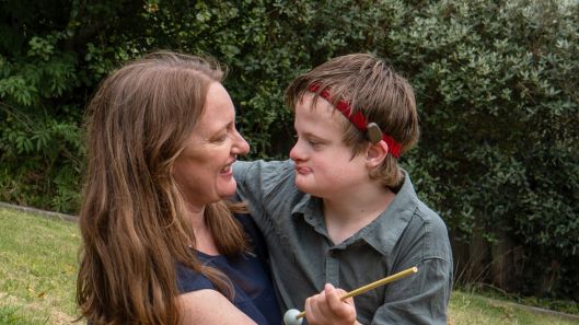 A mother and her son with Down syndrome embrace while looking at each other.