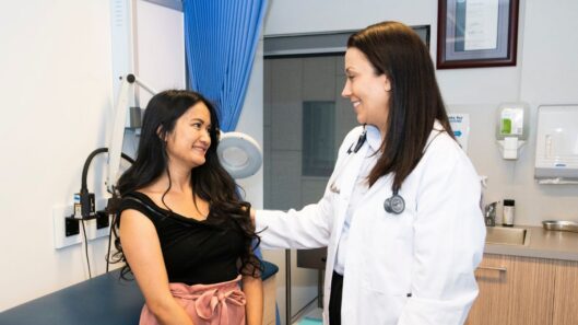 A woman with intellectual disability and a doctor in an exam room. They are both smiling.
