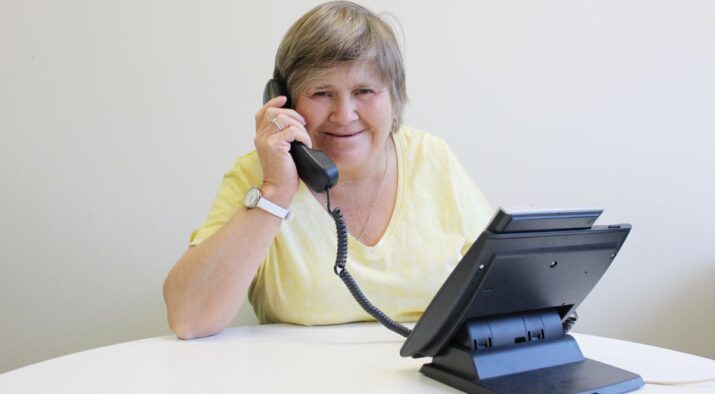 A woman with intellectual disability answers a desk phone.