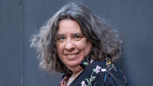 A woman with intellectual disability looks at the camera and smiles.