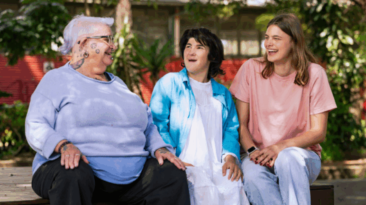 Three women with intellectual disability sit and laugh together.