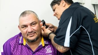 A man with intellectual disability having his ears checked by a health worker.