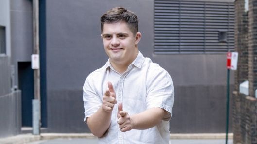 A young man with intellectual disability doing finger guns.