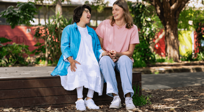Two young women with intellectual disability sit together and laugh.