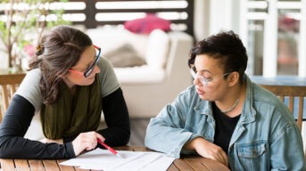 A person with intellectual disability and their supporter look over a document to make a decision