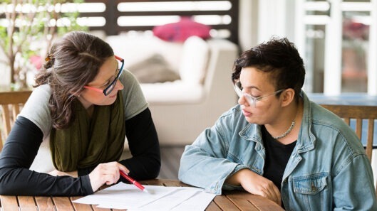 A person with intellectual disability and their supporter look over a document to make a decision