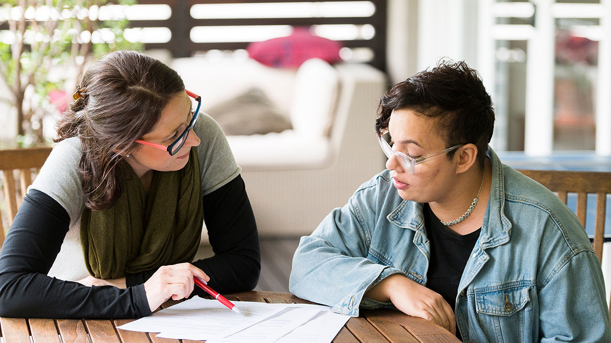 A person with intellectual disability and their supporter look over a document to make a decision